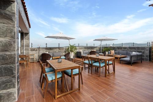 a patio with wooden tables and chairs and umbrellas at Hotel Vista Caribe Azúa in Azua de Compostela