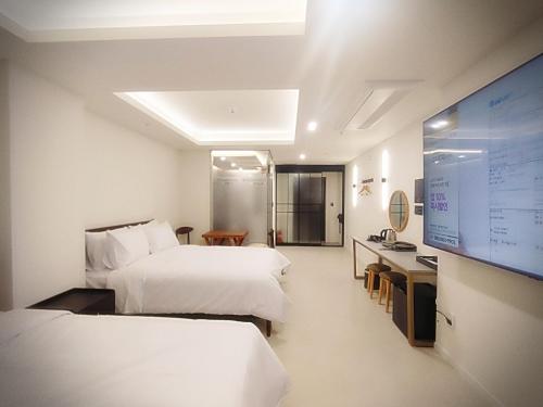 a hotel room with two beds and a flat screen tv at Bluebird Hotel in Incheon