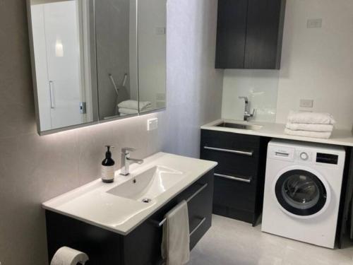 a bathroom with a sink and a washing machine at Two Bedroom Guest House in Remuera Auckland in Auckland