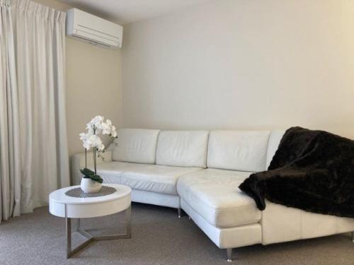 a white living room with a white couch and a table at Two Bedroom Guest House in Remuera Auckland in Auckland