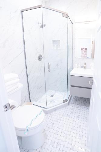 a white bathroom with a shower and a toilet at The Hermitage at Napeague in Amagansett