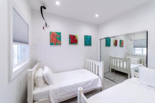 a white bedroom with two beds and a mirror at The Hermitage at Napeague in Amagansett