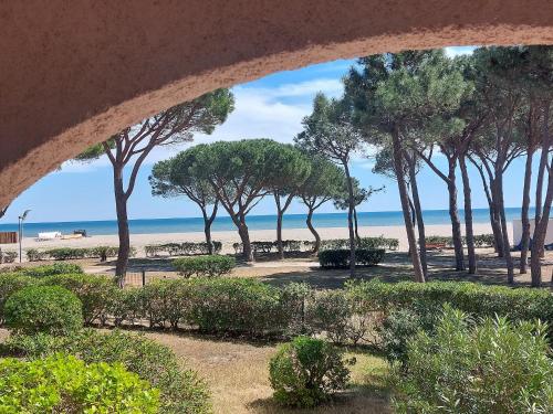 - une vue sur la plage avec des arbres et l'océan dans l'établissement Pavillon climatisé 4/5 pers, grande terrasse, proche plage et commerces, parking sécurisé - FR-1-776-6, à Argelès-sur-Mer