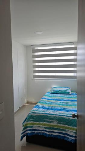 a white bedroom with a bed with a window at Estadía Familiar in Ibagué