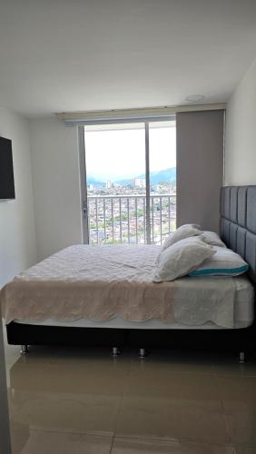 a bed in a room with a large window at Estadía Familiar in Ibagué