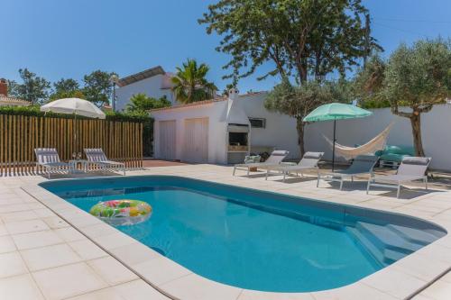 une piscine avec des chaises et un parasol dans l'établissement Casa dos Trevos, 5 Bedroom Villa with Pool, à Lagos