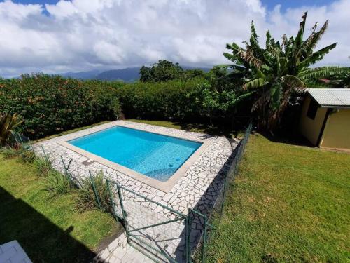 una piscina en un patio junto a un jardín en Fare Hibiscus, en Tohautu
