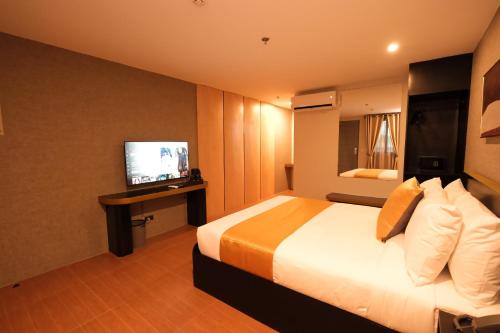 a hotel room with a bed and a television at The Quarters by Rosey in Cabanatuan