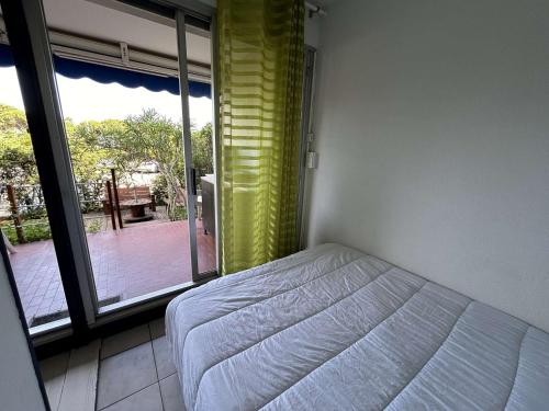 une chambre avec un lit et une grande fenêtre dans l'établissement Appartement avec Piscine, Terrasse et Climatisation - 5 Couchages - Grau-du-Roi - FR-1-250-290, au Grau-du-Roi