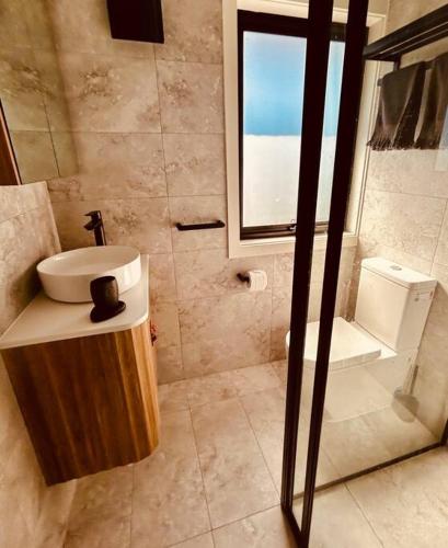 a bathroom with a sink and a toilet and a window at First Tracks Studio in Thredbo