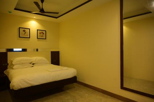 a bedroom with a bed with a ceiling fan and a mirror at La grande suite karaikal in kāraikāl
