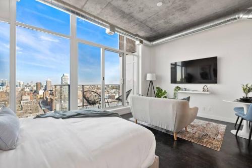 a bedroom with a white bed and a large window at Studio Just Steps from Stampede Park, Luxury Living in Calgary