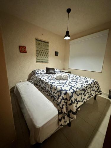 a bedroom with a bed with a black and white blanket at Departamento completo en Acapulco Diamante in La Sabana