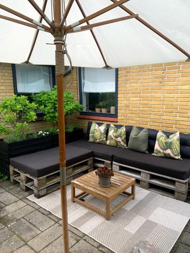 a patio with a black couch and an umbrella at Lovely villa at the foot of the Funen Alps in Fåborg