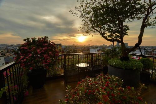 a balcony with flowers and chairs and a sunset at La Siesta Premium Hang Be in Hanoi