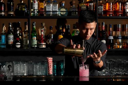 a man standing behind a bar making a pink drink at La Siesta Premium Hang Be in Hanoi