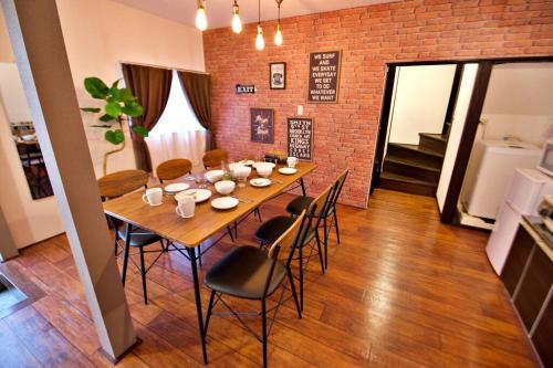a dining room table with chairs and a brick wall at TOMARIE Horikiri Residential Suite in Tokyo