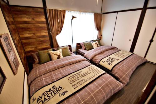 two beds in a small room with a window at TOMARIE Horikiri Residential Suite in Tokyo