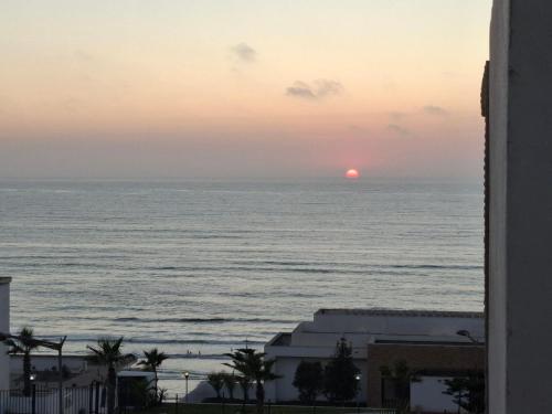 a view of the ocean at sunset from a building at Appt magnifique vue mer et piscine spacieuse in Sidi Bouqnadel