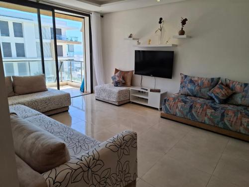 a living room with couches and a flat screen tv at Appt magnifique vue mer et piscine spacieuse in Sidi Bouqnadel