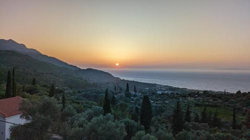 a sunset over a town with trees and the ocean at Villa Luna Home in Vourliótai