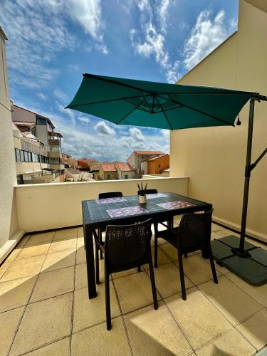 une table et des chaises sur un balcon avec un parasol dans l'établissement Appartement Studio T1bis ALOHA avec terrasse en front de mer, à Capbreton