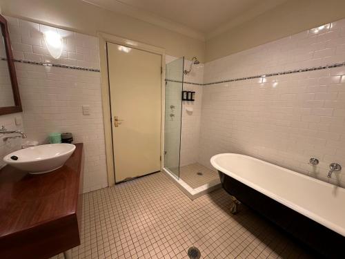 a bathroom with a tub and a sink and a shower at Fitzroy Inn Historic Retreat Mittagong in Mittagong
