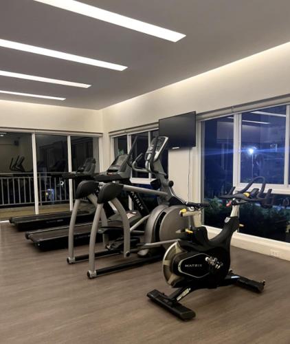 a gym with several tread machines in a room with windows at Cozy Studio Condo in Dumaguete