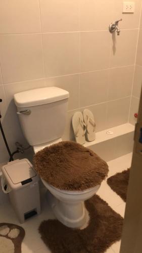 a bathroom with a toilet with a rug on the floor at Cozy Studio Condo in Dumaguete