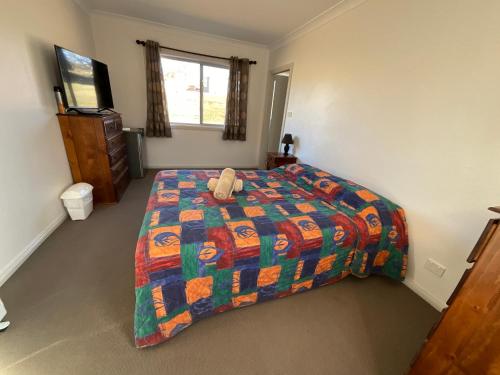 a bedroom with a bed with a teddy bear on it at San Michele Adaminaby in Adaminaby