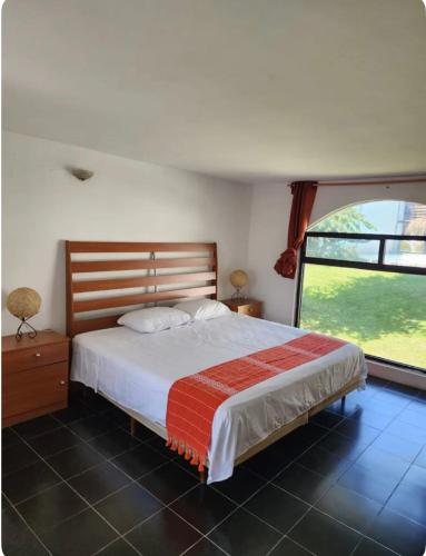 a bedroom with a large bed and a large window at Casa Camelina in Cuernavaca