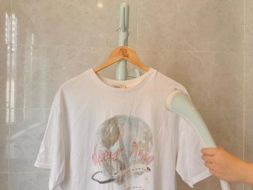 a white shirt is hanging on a hanger at Dayin Youth Hostel - Old Town & People's Square& Rail Hub -Social Area -Bar -Café -Gym -Free Laundry Luggage Storage -24H Front Desk -English Service in Shanghai
