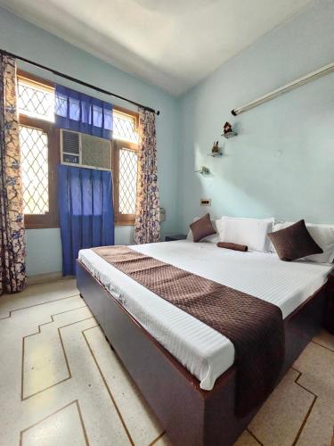a bedroom with a large bed with blue walls and windows at The Green Villa in Ludhiana
