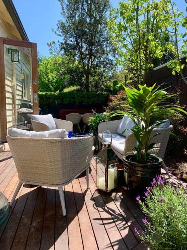a patio with chairs and plants on a wooden deck at The Small House - Mid century gem in wine county's Healesville in Healesville