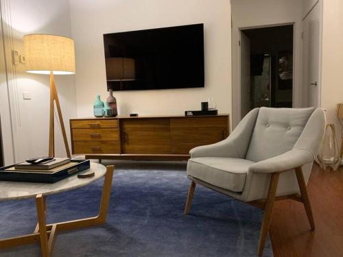 a living room with a chair and a tv at The Small House - Mid century gem in wine county's Healesville in Healesville