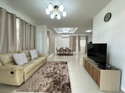 een woonkamer met een bank en een flatscreen-tv bij PS home โฮมฮักขอนแก่น in Ban Non Sa-at
