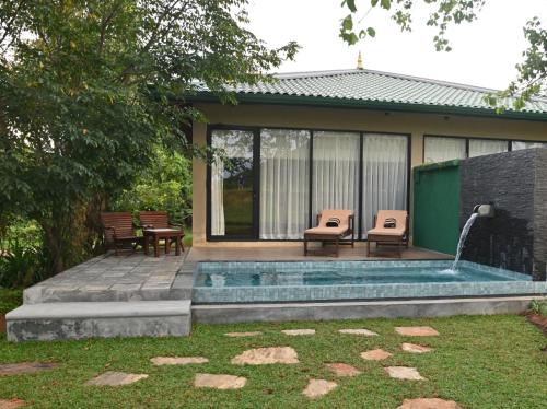 a backyard with a pool with two chairs and a fountain at Sigiriya King's Resort in Sigiriya