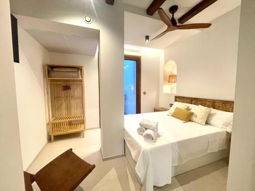 a white bedroom with a bed and a chair at Pepitas House in Valencia