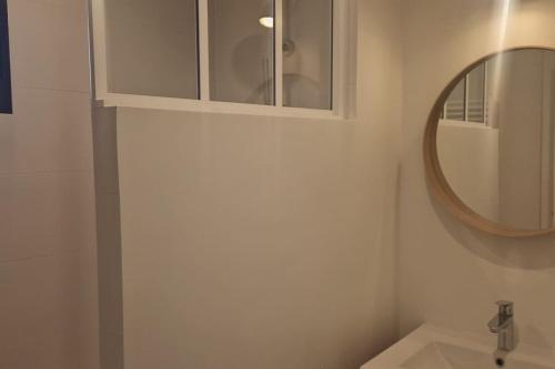 une salle de bain avec un lavabo et un miroir dans l'établissement Le gîte Le Magnolia, à Carnac