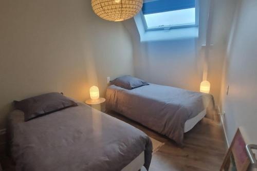 - une chambre avec deux lits et une table avec deux lampes dans l'établissement Le gîte Le Magnolia, à Carnac