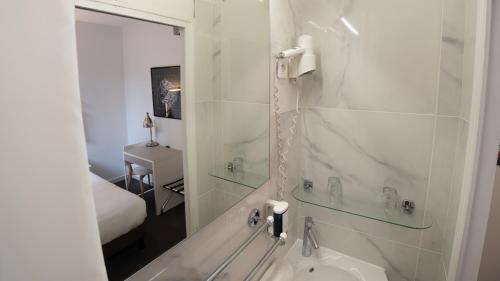 a bathroom with a tub and a shower with a mirror at Brit Hotel Des Grands Hommes - Bordeaux Centre in Bordeaux