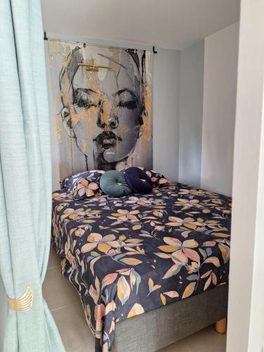 une chambre avec un lit avec une couette fleurie dans l'établissement Mimilou Agathines, au Cap d'Agde