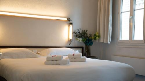 a bedroom with a white bed with towels on it at Hotel Des Grands Hommes - Bordeaux Centre in Bordeaux