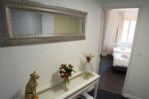 a room with a mirror and a table with flowers at Hotel Des Grands Hommes - Bordeaux Centre in Bordeaux