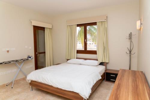 a bedroom with a bed and a table and a window at Two Bedroom Apartment - Hawana Salalah in Ţāqah