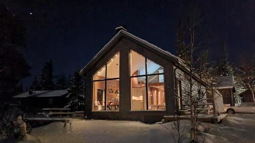 a small house with large glass windows at night at Fjellyx i funäs med relax&bastu, badtunna, 13 bädd in Funäsdalen