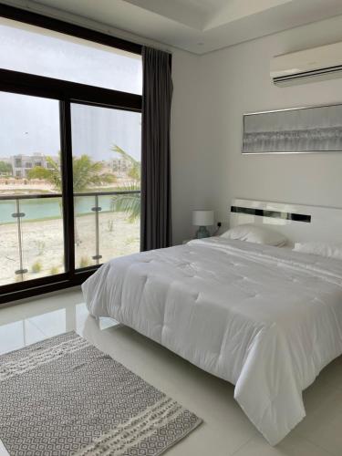 a white bedroom with a large bed with a view of the beach at Stella Salalah in Salalah