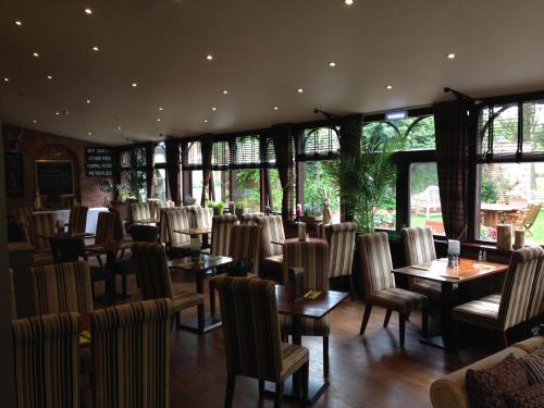 a dining room with tables and chairs and windows at Bowburn Hall Hotel in Durham