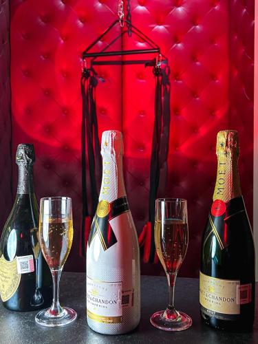 three bottles of champagne and two glasses on a table at Motel Boutique Qatro in Ensenada