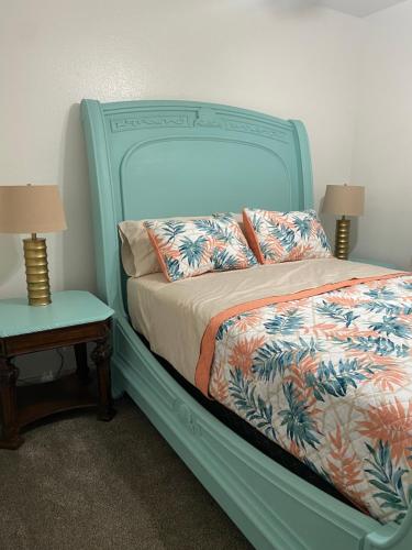 a bed with a blue headboard and two tables with lamps at Casa Linda in Desert Hot Springs